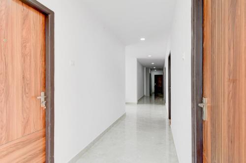 an empty corridor with an open door and white walls at Super Townhouse B N Reddy Formerly Capitol Stay Inn in Surūrnagar