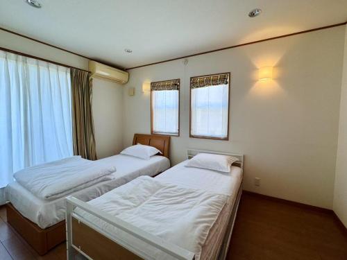 two beds in a room with two windows at スペース海浜幕張ハウス in Chiba