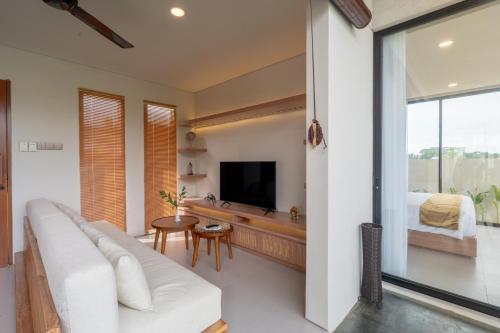 a living room with a white couch and a television at Tuspa Ubud Villa in Ubud