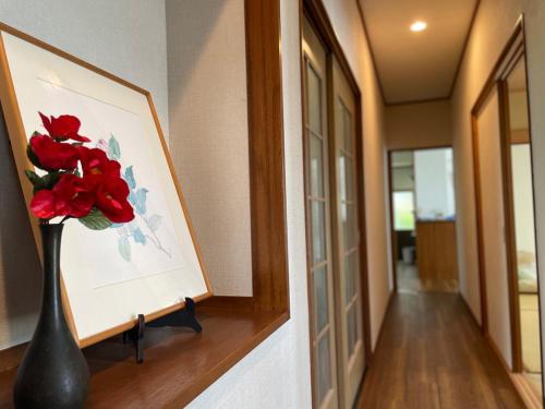 a vase with red flowers sitting on a shelf in a hallway at TheOceanVilla Sole in Oshima