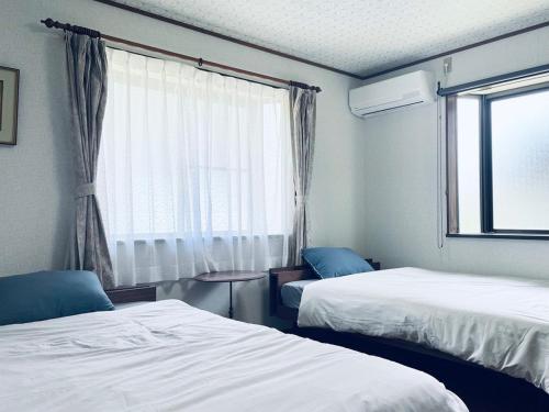 a hotel room with two beds and a window at TheOceanVilla Sole in Oshima
