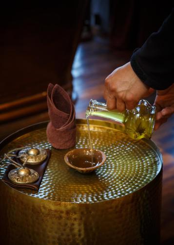 a person pouring sauce into a bowl in a table at Kavya Himalayas in Nagarkot