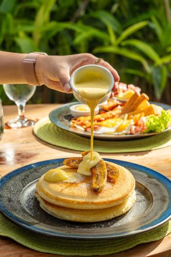 a person drizzling sauce onto a plate of pancakes at Balai Adlao in El Nido