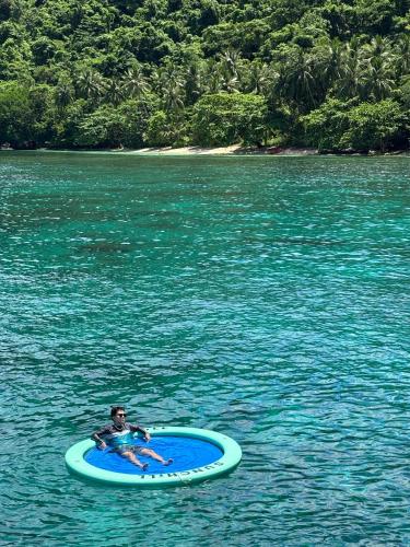 a man laying on a surfboard in the water at Balai Adlao in El Nido