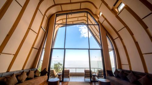 an empty room with a large window and chairs at Kavya Himalayas in Nagarkot