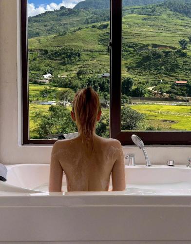 a woman sitting in a bath tub looking out a window at Boutique En Hotel Sapa in Sa Pa
