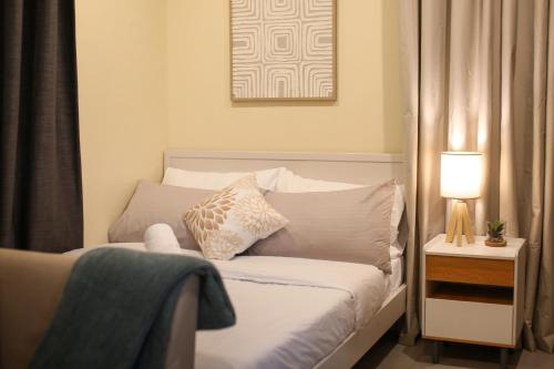 a small bedroom with a bed with white pillows at Cebu Central Charm Balcony City View - StoryStays in Cebu City