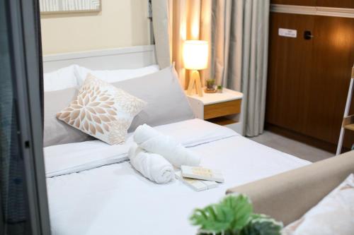 a bed with white sheets and pillows on it at Cebu Central Charm Balcony City View - StoryStays in Cebu City