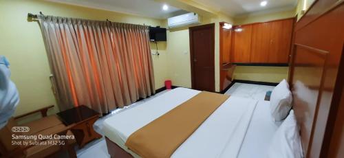 a bedroom with a large white bed and a window at Hotel Staar World in Kanyakumari