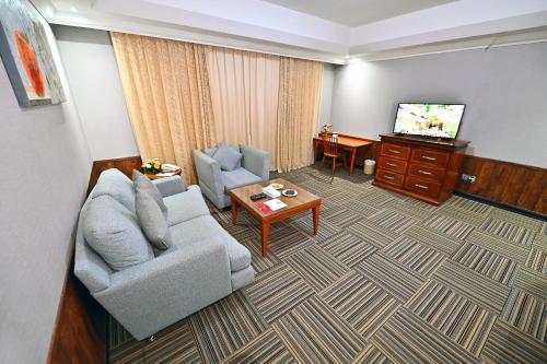 a living room with a couch and a tv at Ewan Ajman Suites Hotel in Ajman 