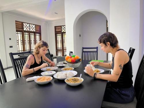 two women sitting at a table with bowls of food at Azure Stay in Kurunegala