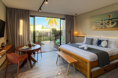 ein Schlafzimmer mit Bett und Tisch und ein Esszimmer in der Unterkunft Studio Alva na Praia de Lages, Rota dos Milagres in Tatuamunha