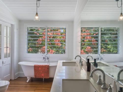 a bathroom with two sinks and a tub and two windows at Fig Tree House in Teven
