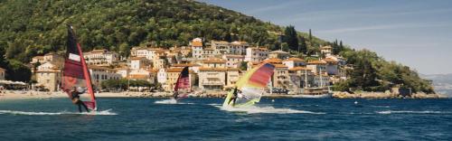 three sailboats in the water in front of a town at Mir u prirodi in Mošćenička Draga