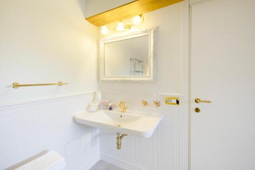 a white bathroom with a sink and a mirror at VILLA TOJI luxury private in Bracciano