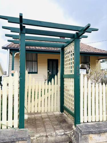 a white fence with a green gate in front of a house at 3-Bedroom Blue Mountains Hideaway in Central Katoomba in Katoomba