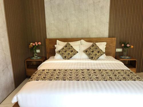 a bed with two pillows and two vases with flowers at Titian Dewi Private Villa Ubud - Close to Cretya Day Club in Tegalalang