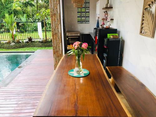 a wooden table with a vase of flowers on it at Titian Dewi Private Villa Ubud - Close to Cretya Day Club in Tegalalang
