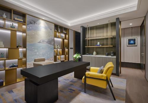 a office with a black desk and yellow chairs at The Azure Ningbo, Vignette Collection in Ningbo