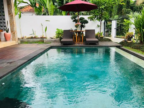 a swimming pool with a table and an umbrella at Titian Dewi Private Villa Ubud - Close to Cretya Day Club in Tegalalang
