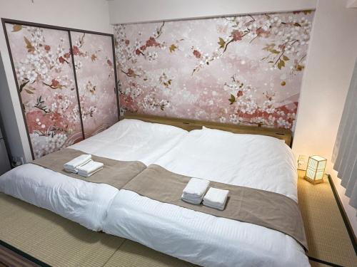 a bedroom with a large bed with two towels on it at Camelot Home in Fukuoka