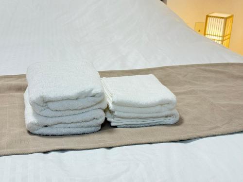 a pile of towels sitting on top of a bed at Camelot Home in Fukuoka