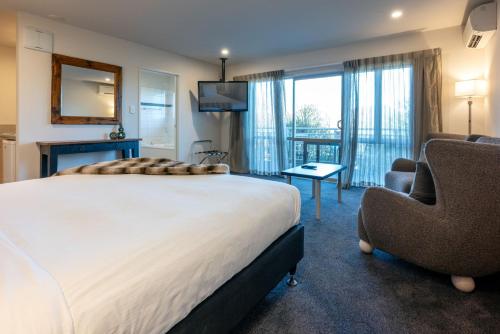 a bedroom with a large bed and two chairs at Hanmer Springs Gateway Lodge in Hanmer Springs
