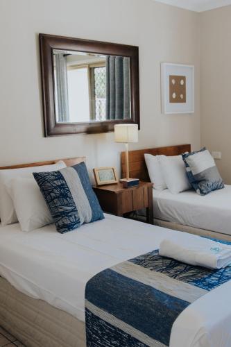a bedroom with two beds and a mirror on the wall at Pandanus Palms Holiday Resort in Point Lookout
