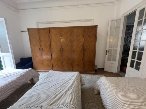 a bedroom with two beds and a wooden cabinet at Granada private bedroom for men only in Alexandria