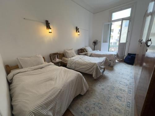a room with three beds and a window at Granada private bedroom for men only in Alexandria