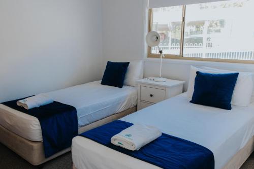 two beds in a room with blue and white at Pandanus Palms Holiday Resort in Point Lookout