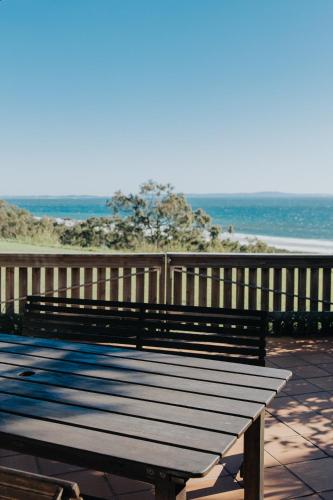 a bench sitting on a boardwalk near the beach at Pandanus Palms Holiday Resort in Point Lookout