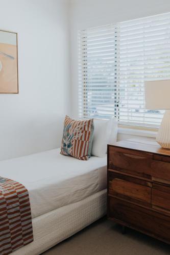 a white bedroom with a bed and a window at Pandanus Palms Holiday Resort in Point Lookout