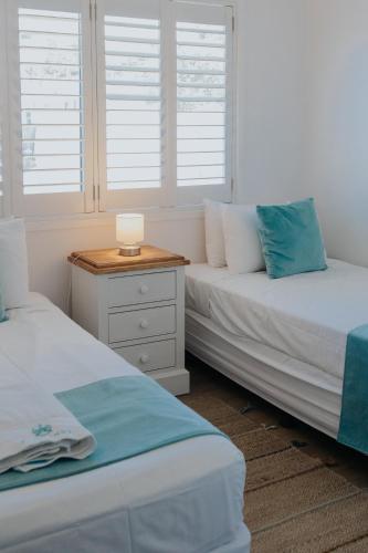 two beds in a room with windows and a table at Pandanus Palms Holiday Resort in Point Lookout