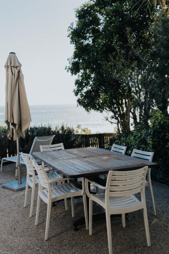 a wooden table and chairs with an umbrella and the ocean at Pandanus Palms Holiday Resort in Point Lookout
