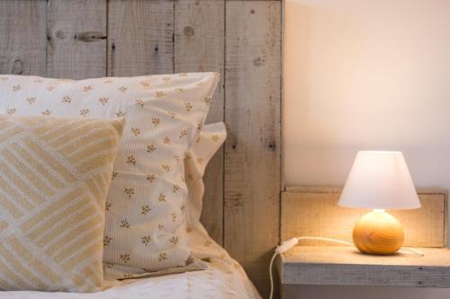 a bed with a pillow and a lamp on a table at Gite du platane in Bélis
