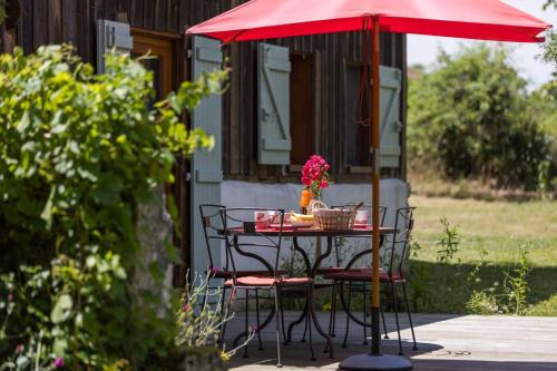 a table with a red umbrella on a patio at Gite du platane in Bélis