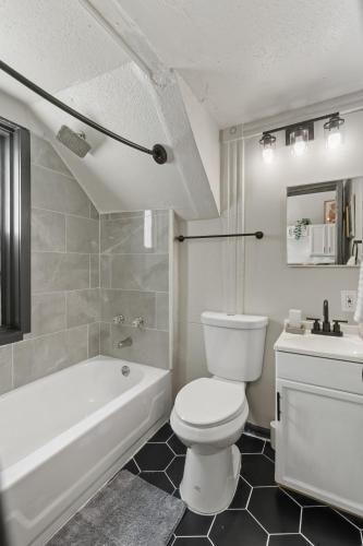 a bathroom with a toilet and a tub and a sink at 2BD Flat Near Cherokee Arts with Game Room vibes! in Saint Louis