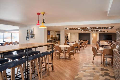 a restaurant with tables and chairs and a bar at Holiday Inn Express London Limehouse by IHG in London