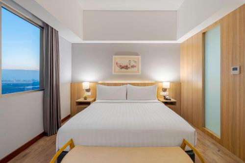 a bedroom with a large white bed and a window at Aston Gresik Hotel & Conference Center in Gresik