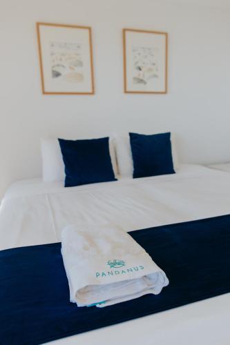 a white bed with blue pillows and a towel on it at Pandanus Palms Holiday Resort in Point Lookout