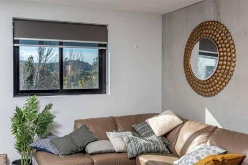 sala de estar con sofá marrón y espejo en The Barty by Parbery Property, en Kingston 