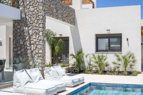 a villa with a swimming pool and two lounge chairs at Nostos Luxury Apartments in Kremasti
