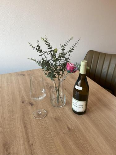 a bottle of wine and a vase of flowers on a table at Verde Apartment in Svoboda nad Úpou