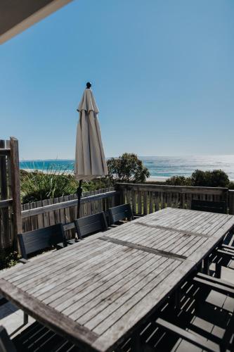 a wooden table with an umbrella and chairs and the beach at Pandanus Palms Holiday Resort in Point Lookout