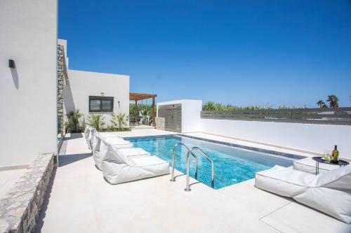 a swimming pool with lounge chairs next to a house at Nostos Luxury Apartments in Kremasti