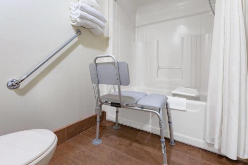 a bathroom with a chair next to a bath tub at Travelodge by Wyndham Bracebridge in Bracebridge