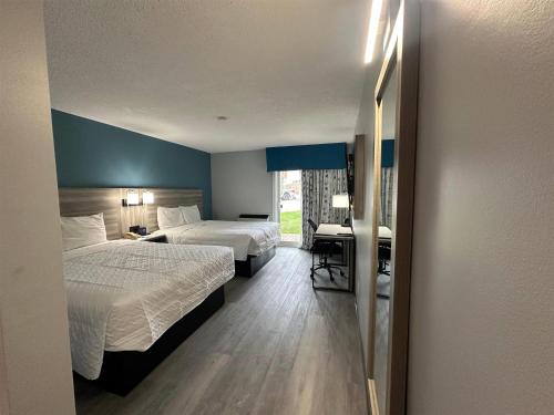 a hotel room with two beds and a desk at Travelodge by Wyndham Bracebridge in Bracebridge