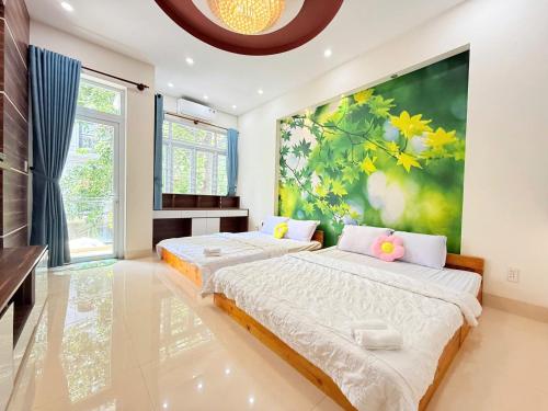 zwei Betten in einem Zimmer mit einem Gemälde an der Wand in der Unterkunft Thiên Kim Homestay in Vũng Tàu