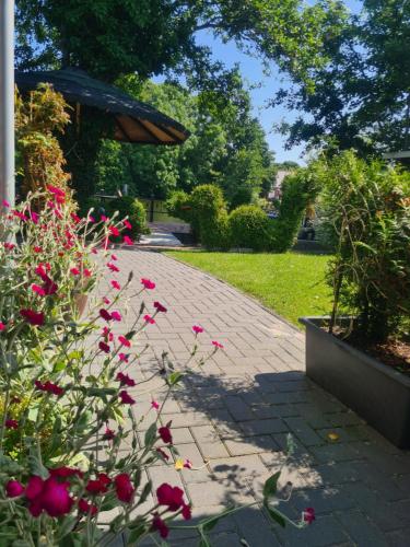 a brick walkway with red flowers and an umbrella at Pension Seeufer Norddeich in Norddeich